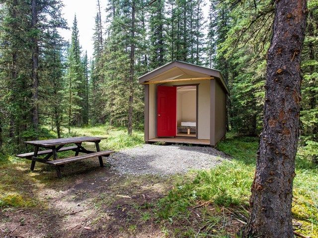 A Mukwah Cabin with a picnic table out front.