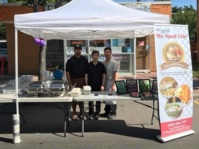 Tent with food trays and banner for The New Mr. Spud Café at an outdoor event