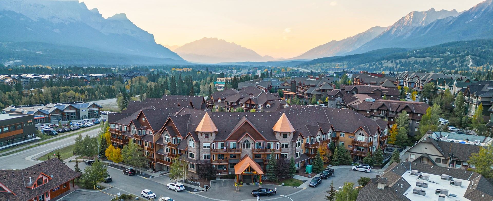 This is a view of a mountain resort, with multiple buildings and surrounding nature. The majestic mountains provide a scenic backdrop to the property.