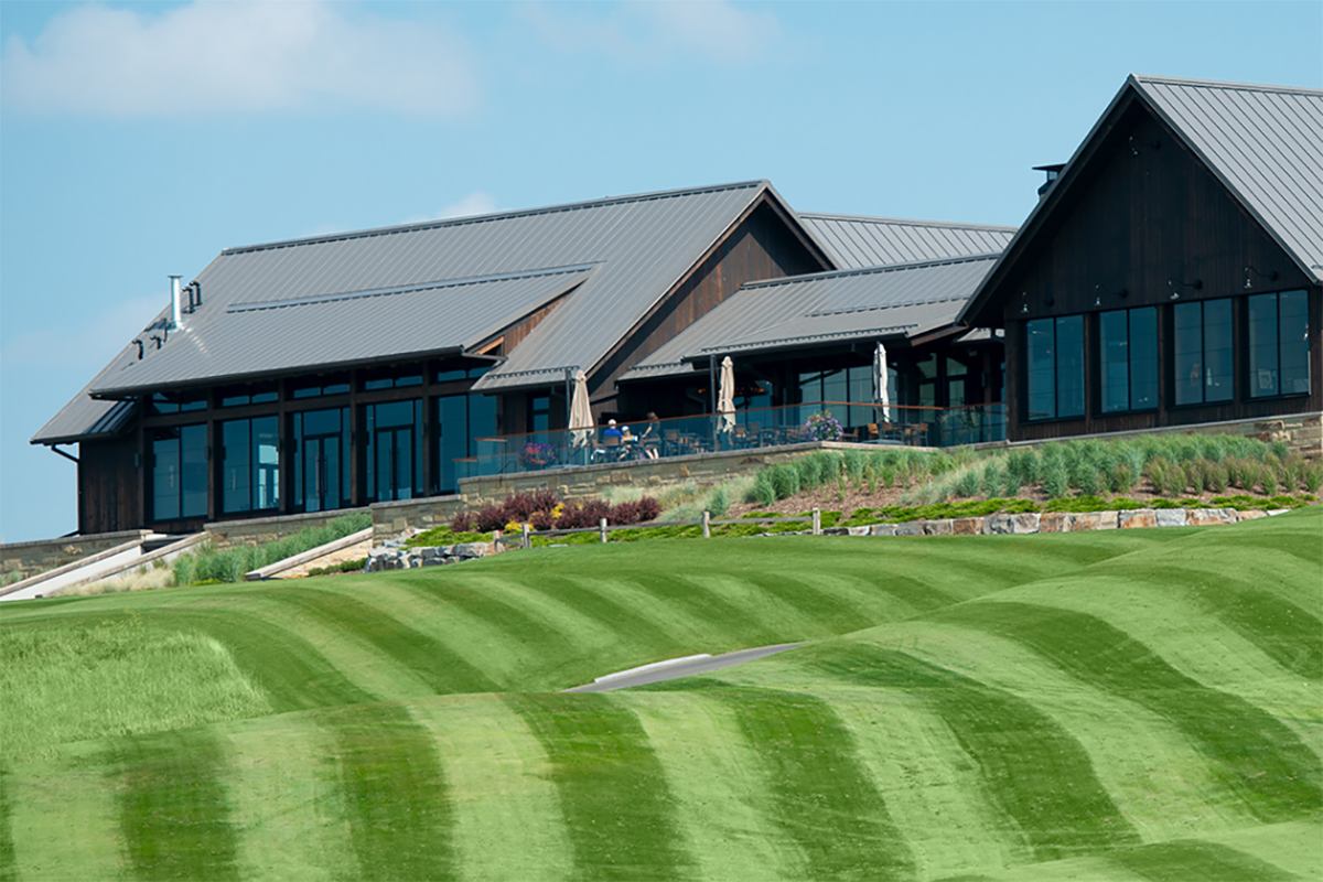 The Bearspaw Golf Club clubhouse with rolling grass in the foreground.
