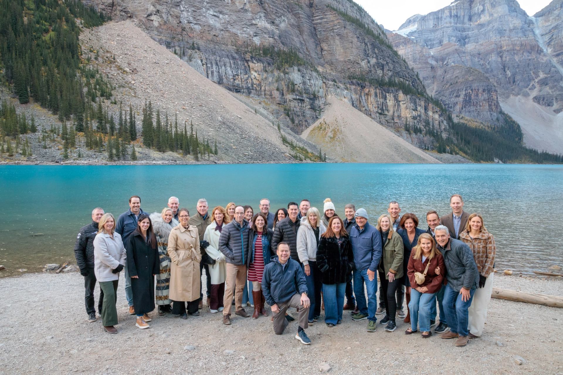 Group photo by a turquoise lake surrounded by mountains.