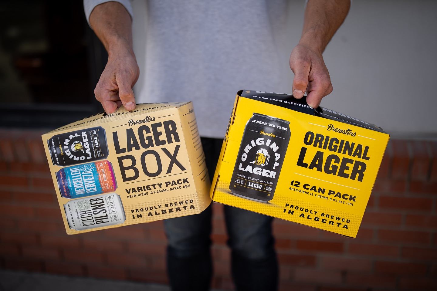 A man carrying a couple cases of Brewsters beverages.