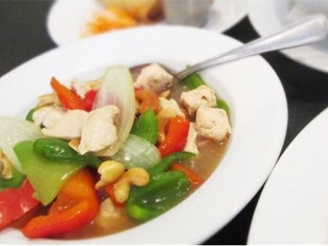 Stir-fried chicken with peppers, onions, and cashews on a white plate.
