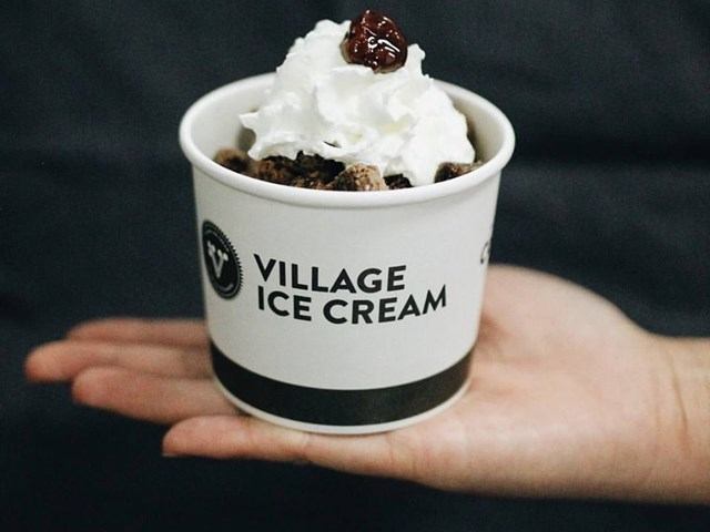 Ice-cream cup with “Village Ice Cream” label on a person’s open palm.