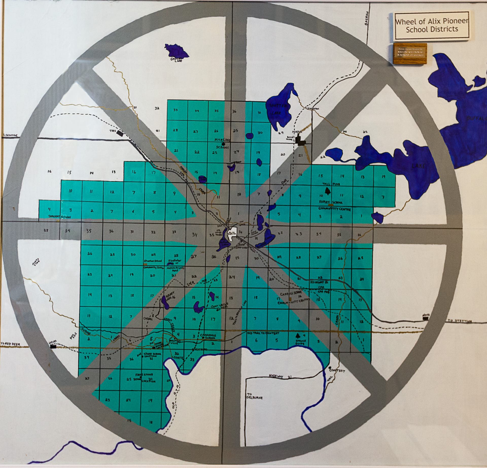 Circular wall map showing the Wheel of Alix Pioneer School Districts with sections, lakes, and roads.