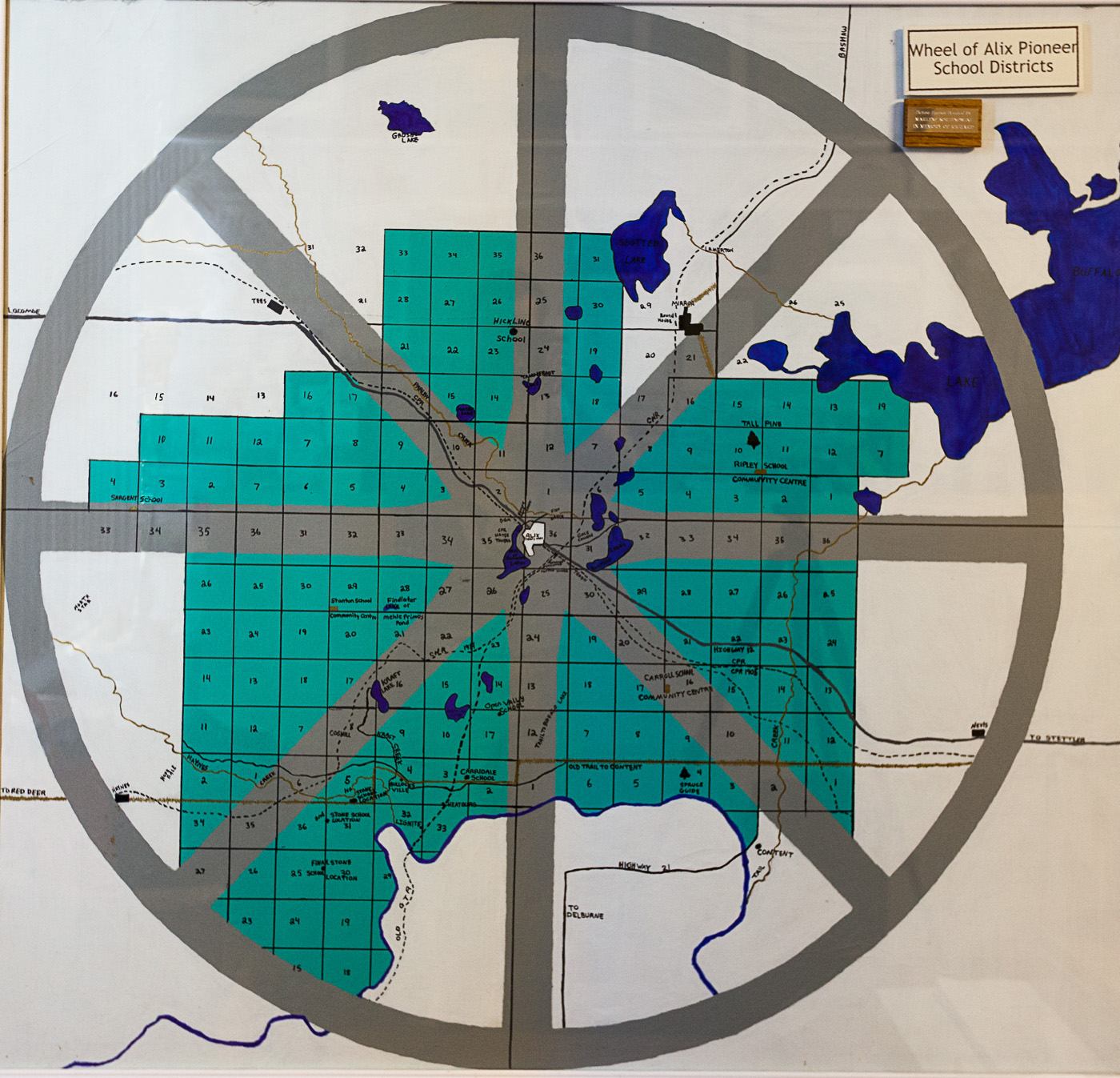 Circular wall map showing the Wheel of Alix Pioneer School Districts with sections, lakes, and roads.