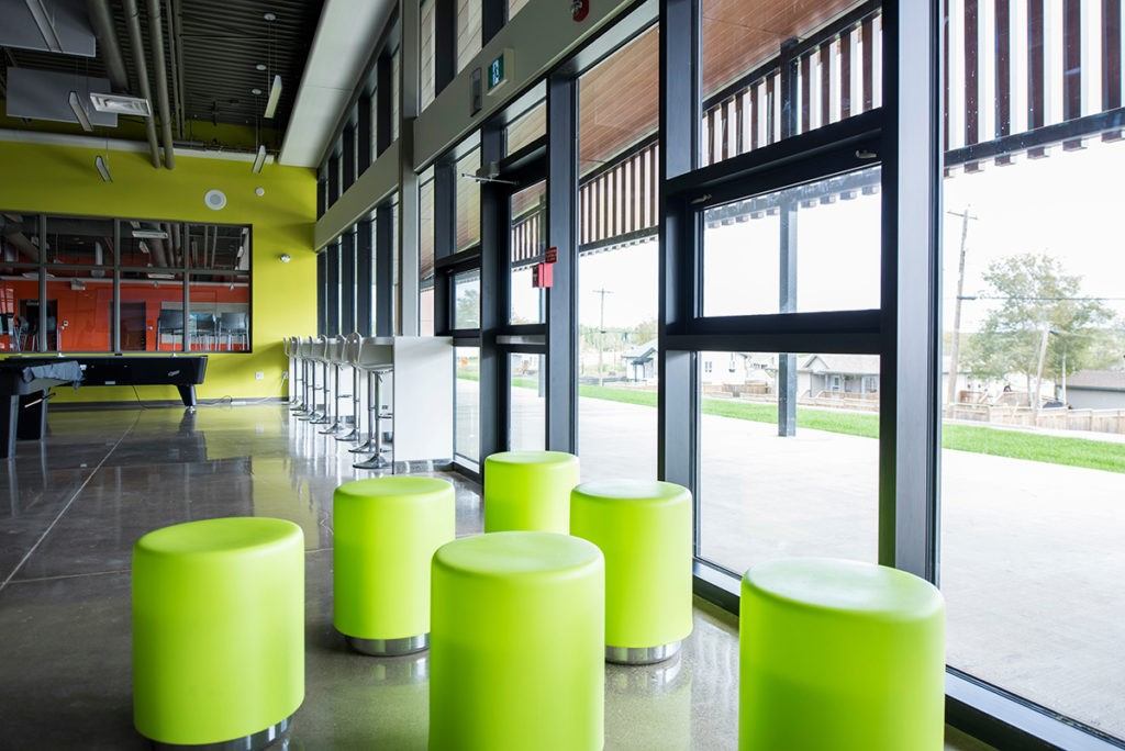 Lobby interior with green ottoman seating, large windows, and a pool table against the wall.