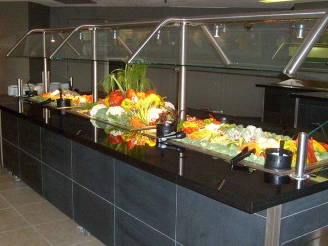 Fresh salad buffet with utensils and sneeze guard.