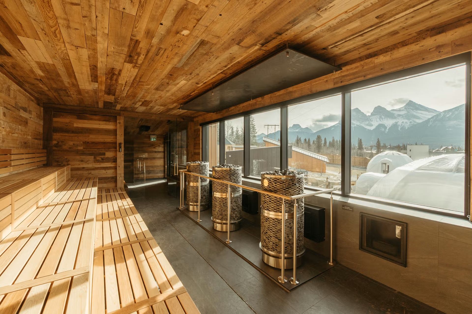 Wood-paneled sauna with large windows overlooking Rocky Mountains at Everwild Canmore.
