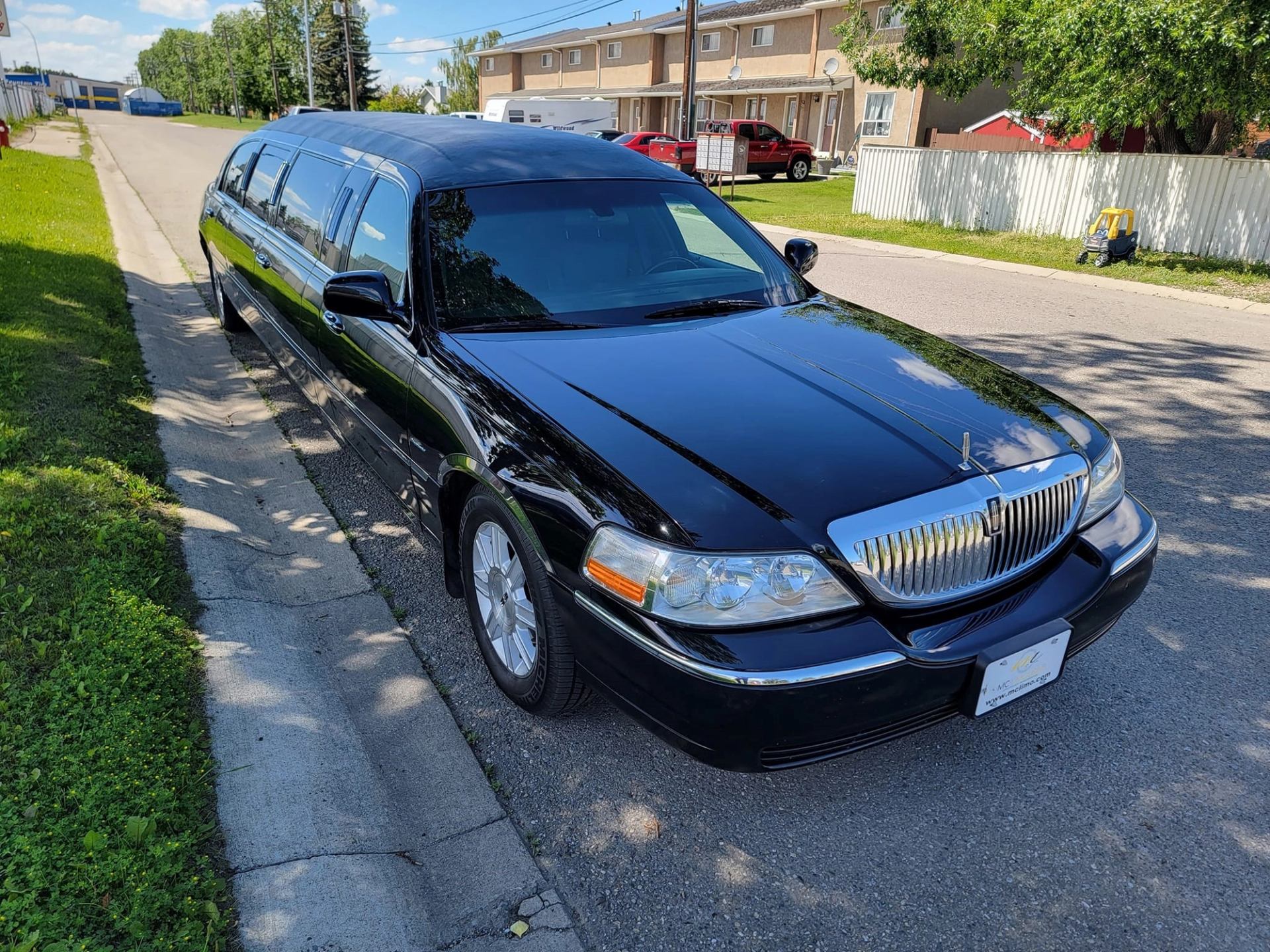 Black stretch limousine parked on a residential street by MC Limousine.