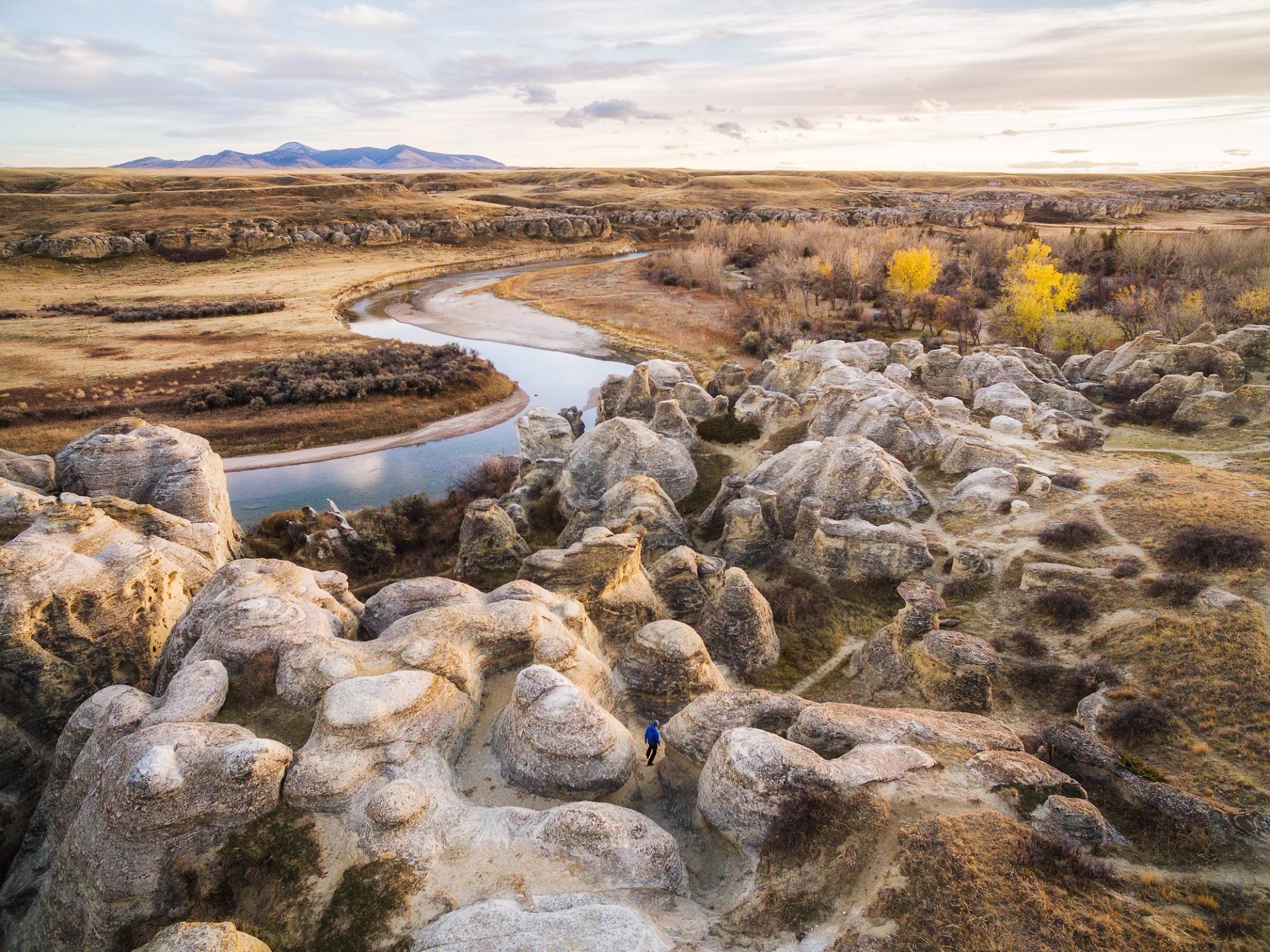 Wide shot of hiker walking through hoodoos.