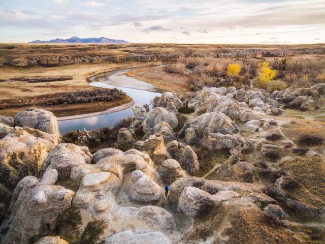 Wide shot of hiker walking through hoodoos.