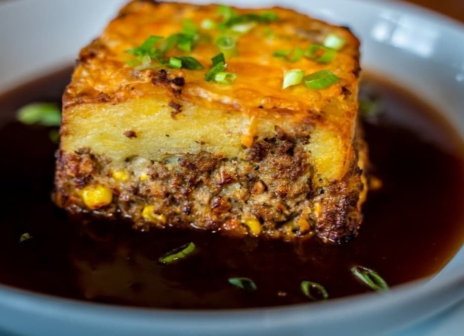 Meatloaf topped with mashed potatoes, cheese, and green onions in rich gravy.