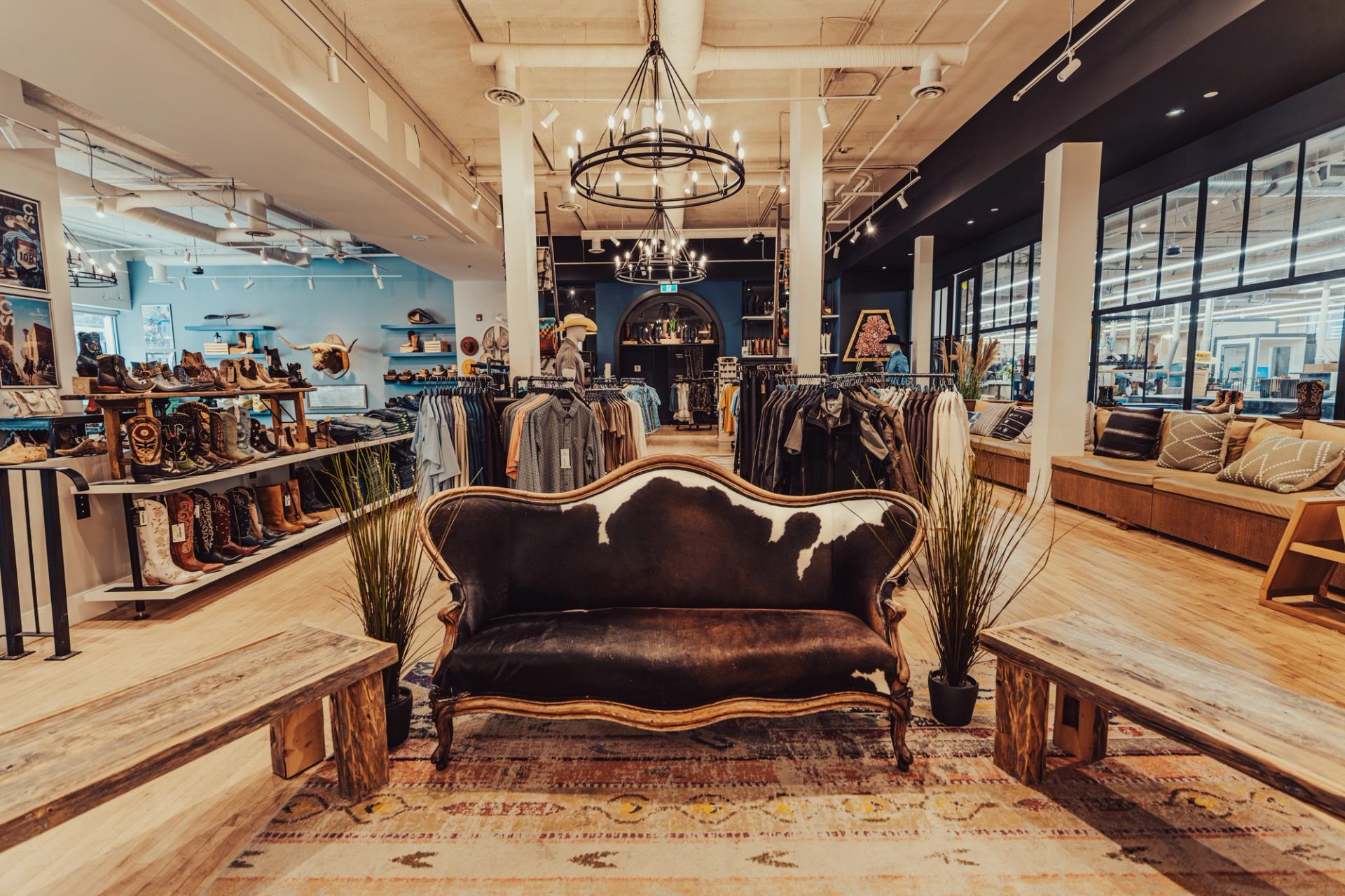 Western clothing store interior with cowhide sofa, boot displays and hanging shirts.