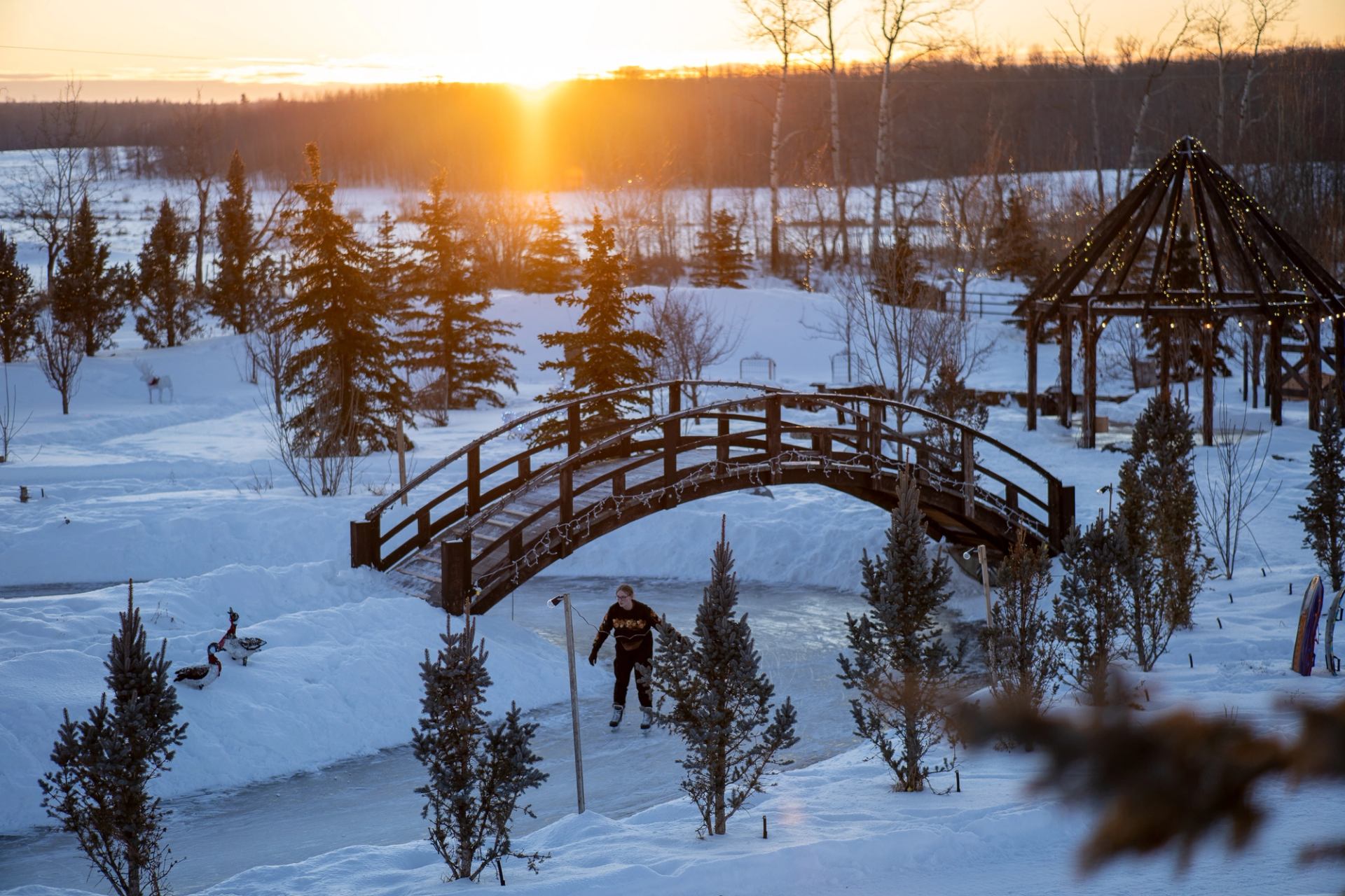 Snowy bridge and gazebo at sunset during Winter Wonderland Festival.