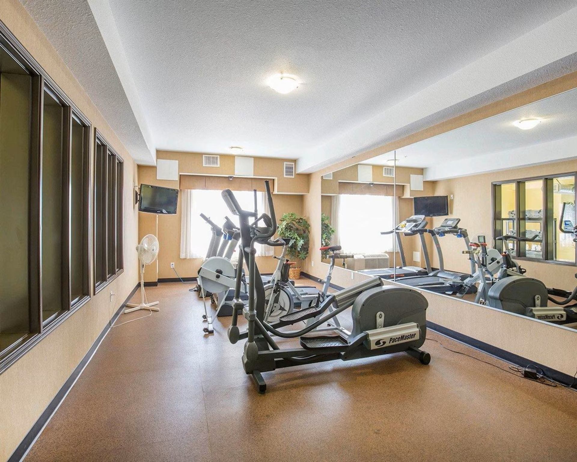 Fitness center at Comfort Inn & Suites with ellipticals, treadmills, mirrors, and TVs.