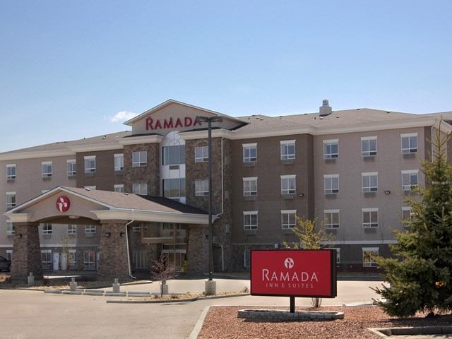 Exterior of Ramada Drumheller hotel with clear blue sky.