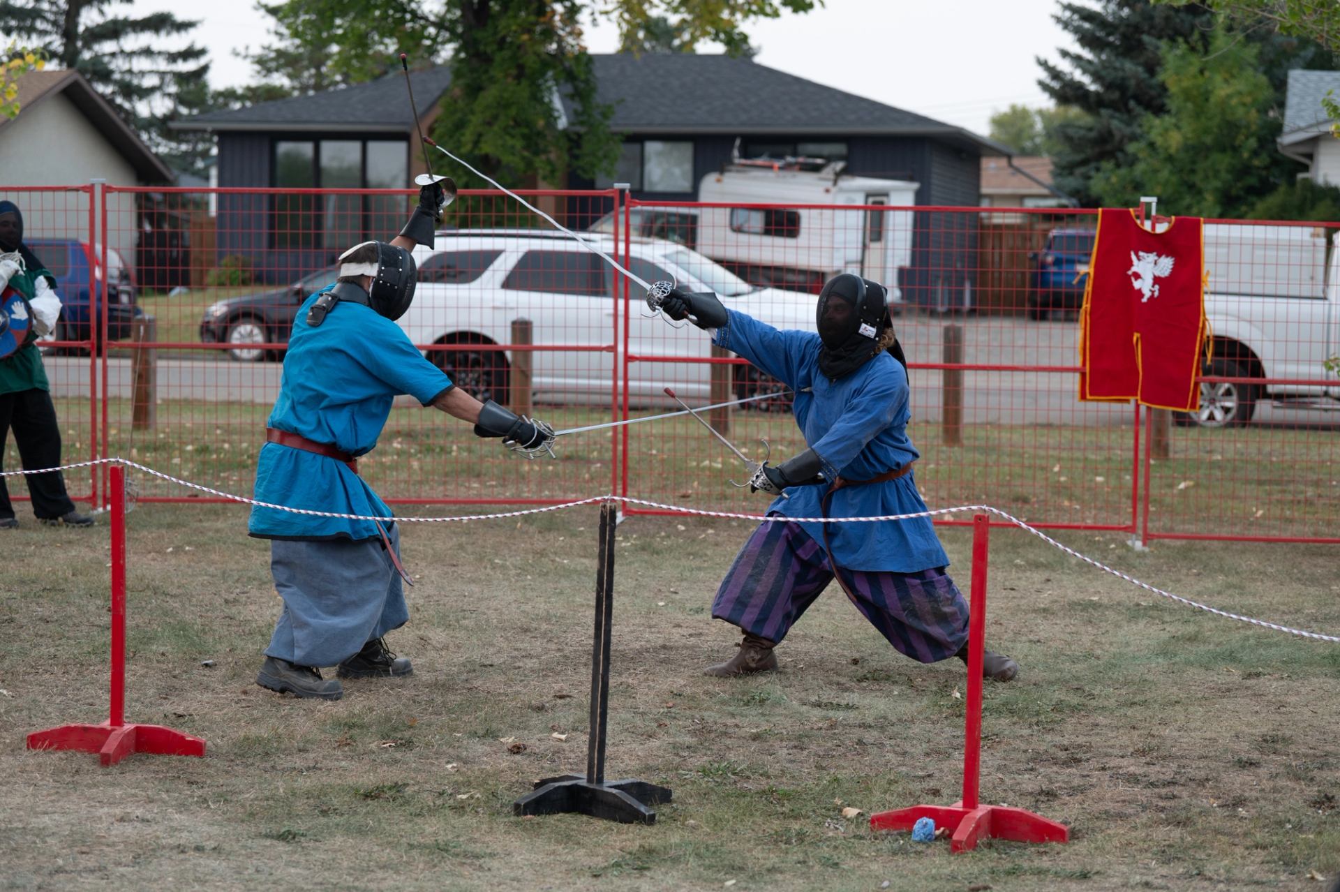 Two armoured participants sword-fighting inside a roped-off arena.