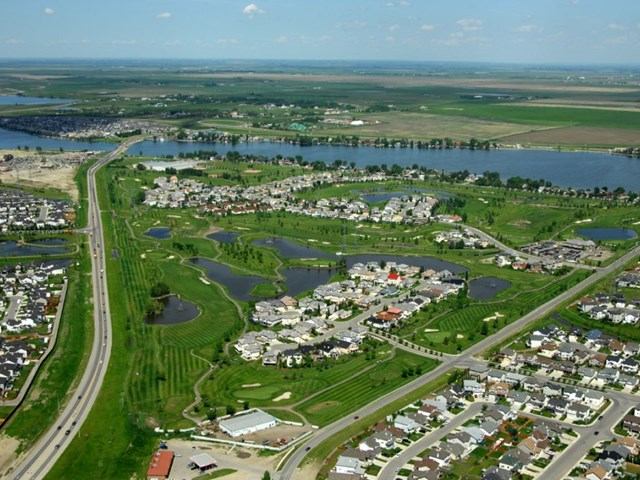 Aerial view of Lakeside Golf course with green fairways, bunkers, and nearby homes by water.