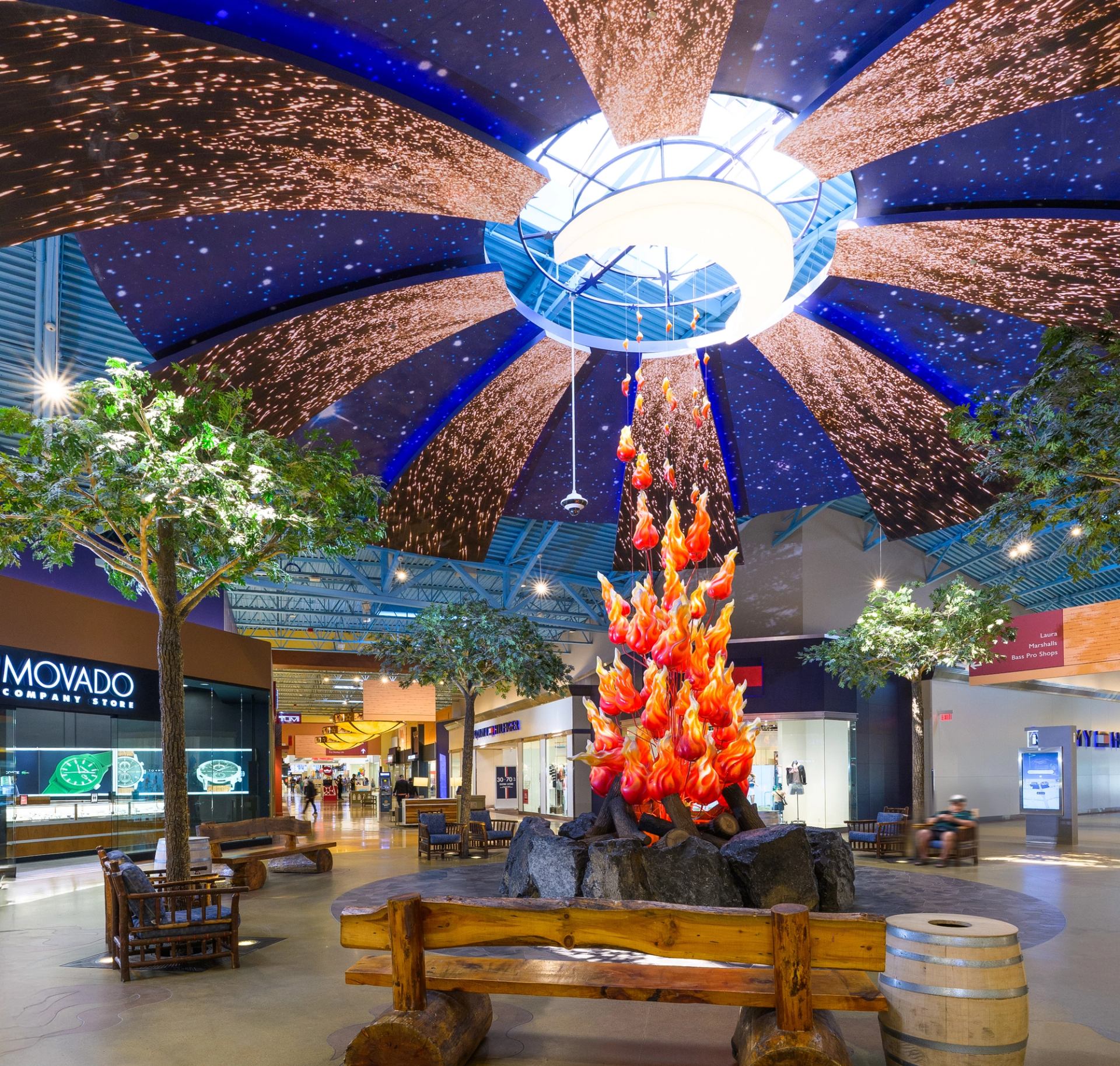Indoor mall with starry ceiling, campfire art, and log benches at CrossIron Mills.