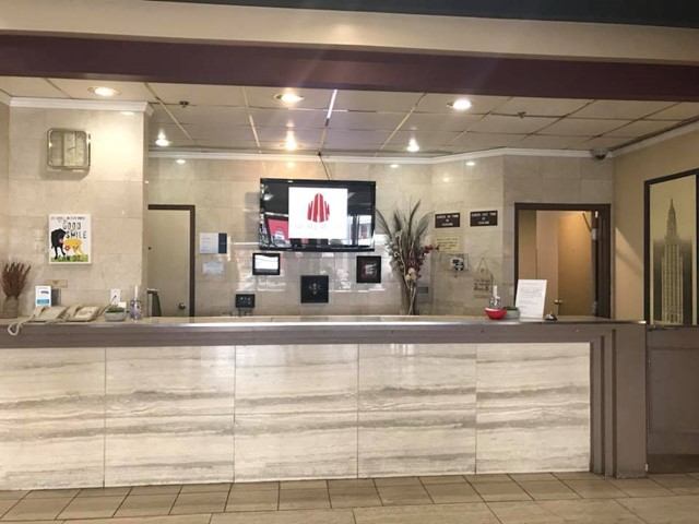 Hotel front desk with marble-style counter, TV display, and decorative accents.