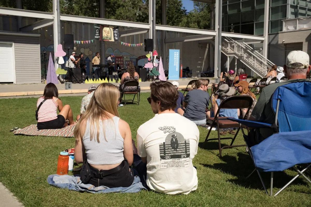 Festival goers sitting on the grass enjoying the concert.
