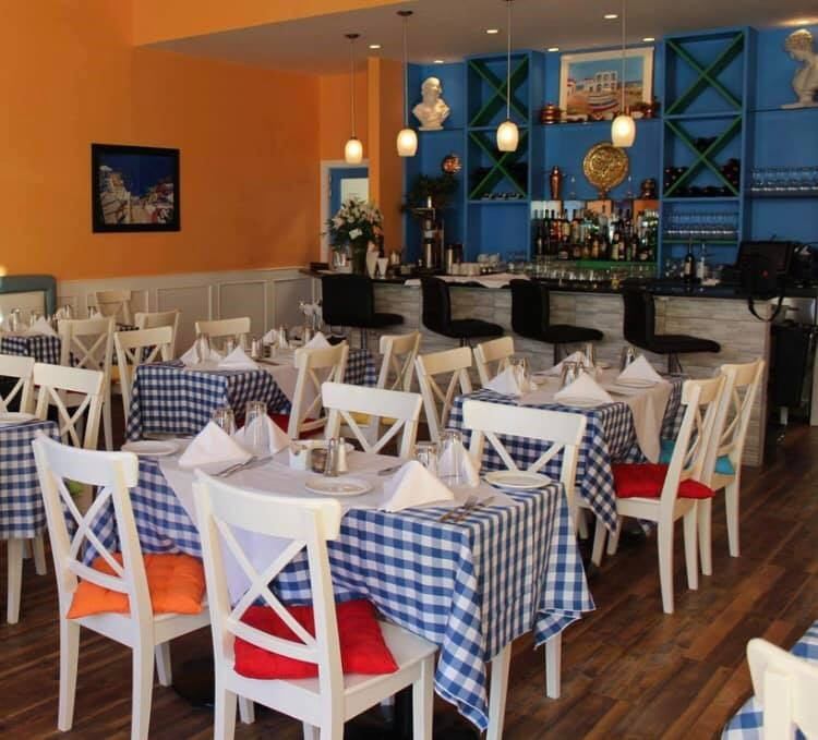 Dine in style at Plaka Greek Taverna—classic checkered tables, warm tones, and a welcoming bar.