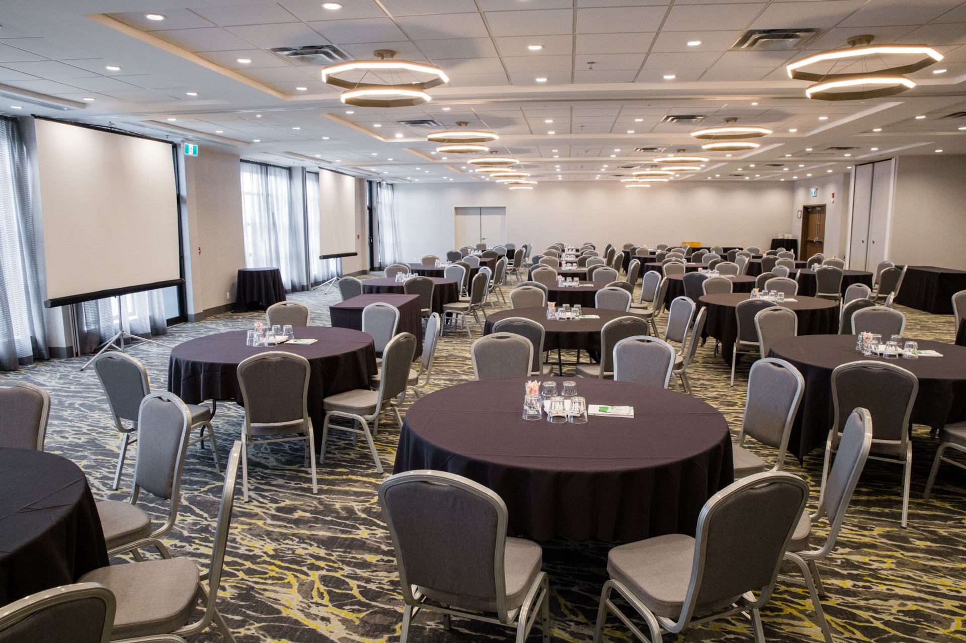 Conference room with round tables, black tablecloths, and gray chairs.