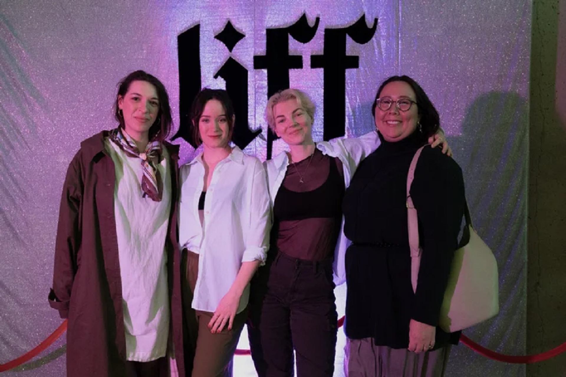 Four women smiling in front of a shimmering backdrop with "Liff" text and a red rope.