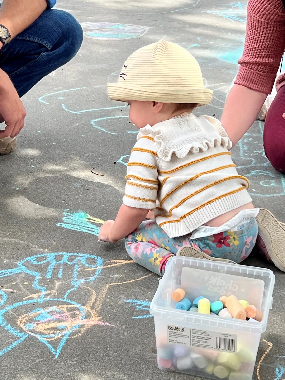 Child drawing colorful chalk art on the pavement at the market