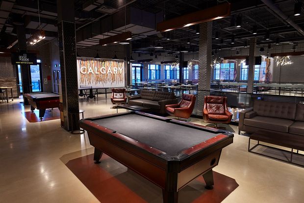 A pool table with lounge chairs in the background.