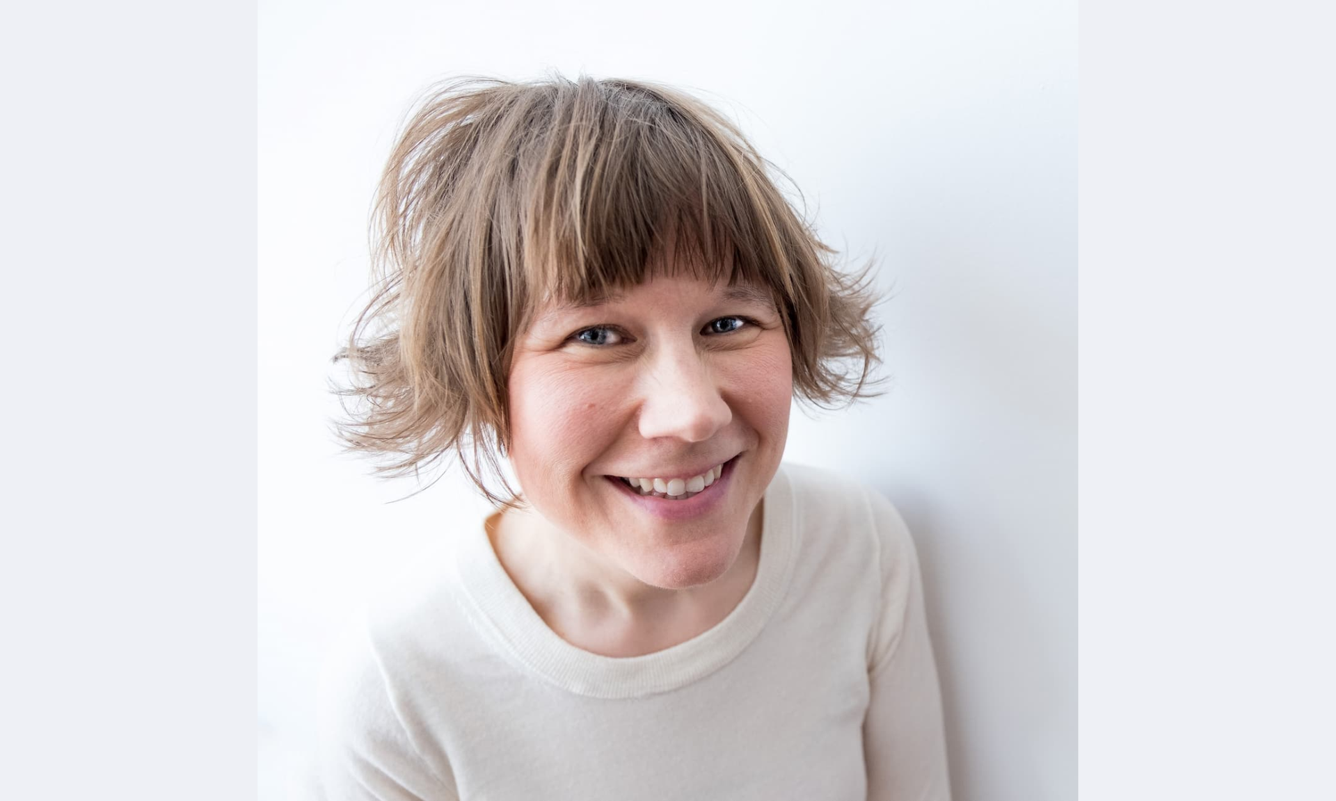 A smiling woman with short, messy brown hair and bangs.