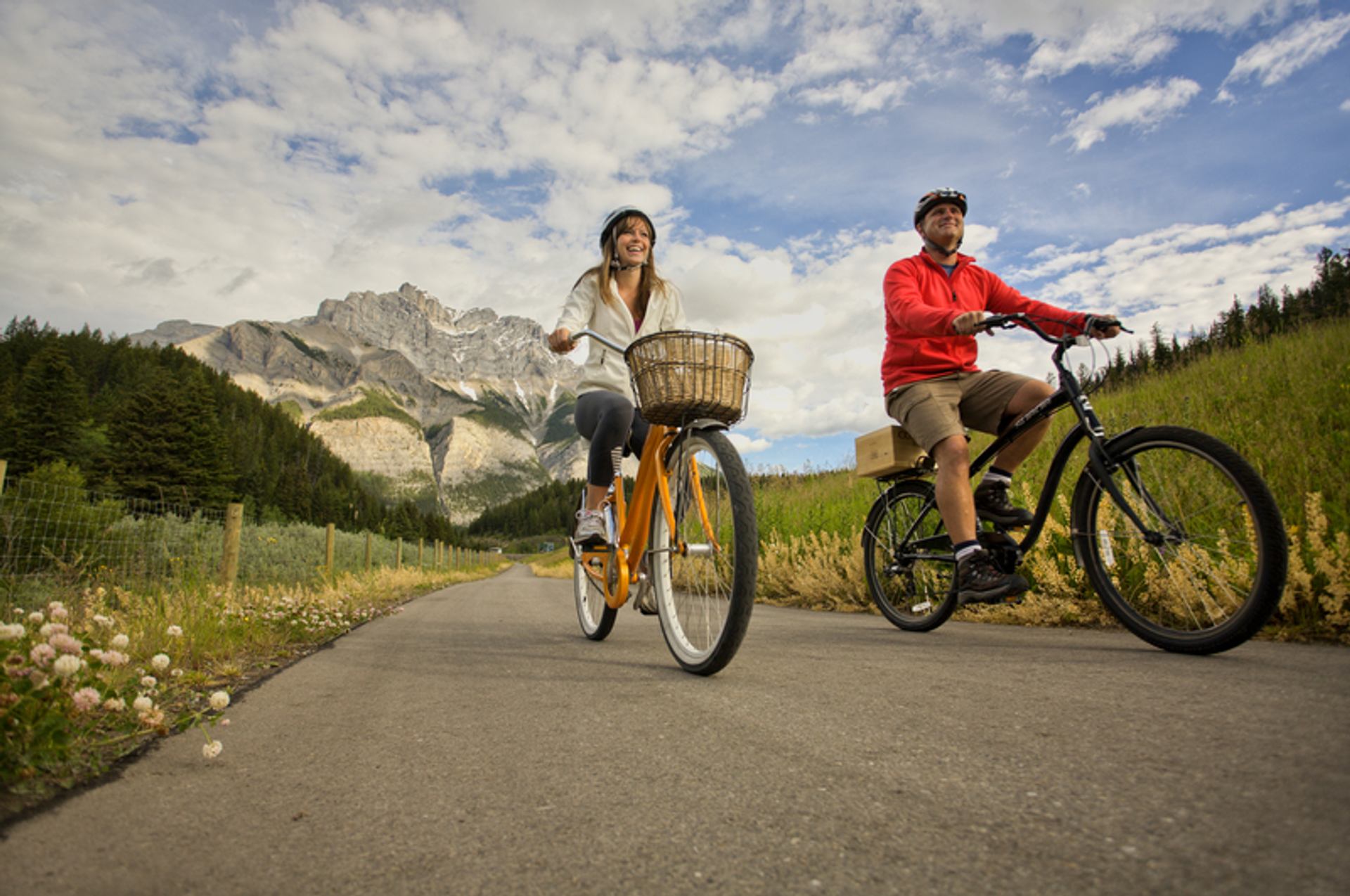 Couple riding bikes along a pathway with mountains in the background