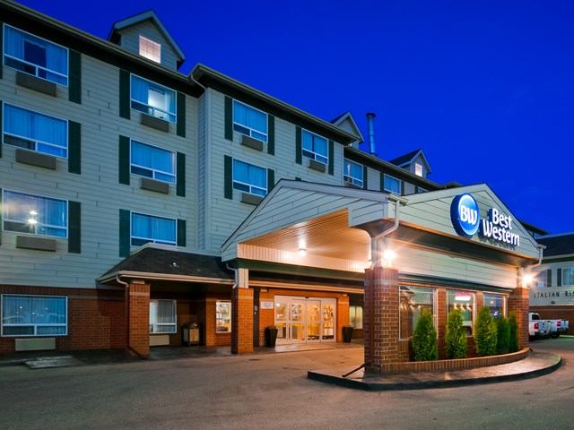Best Western hotel entrance with illuminated awning and windows under a blue sky.