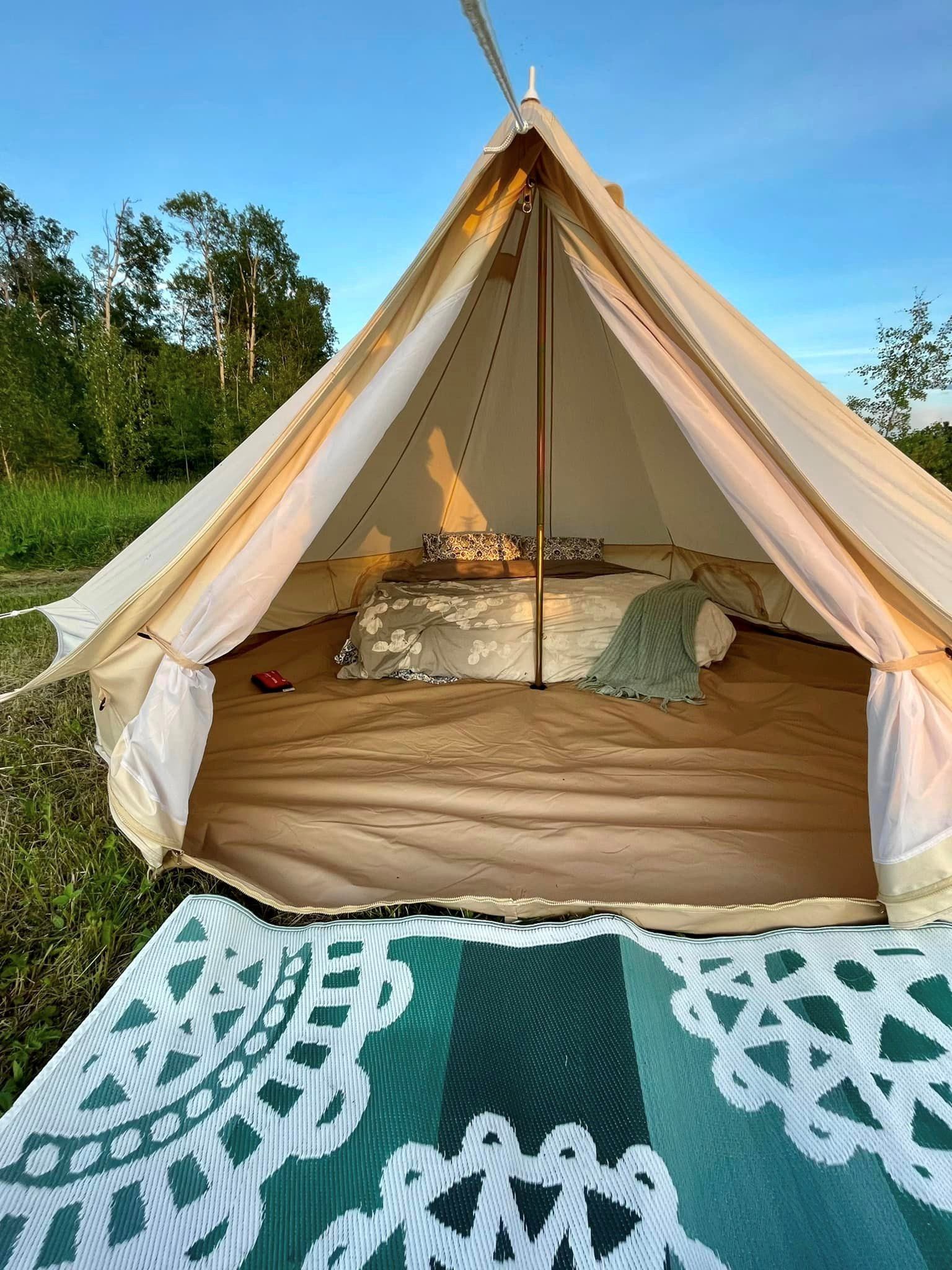 Inside a canvas tent with bed and patterned rug outdoors
