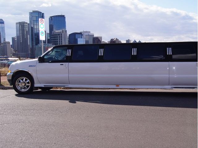 White A-1 Limousine parked roadside with city skyline and street signs in the background.