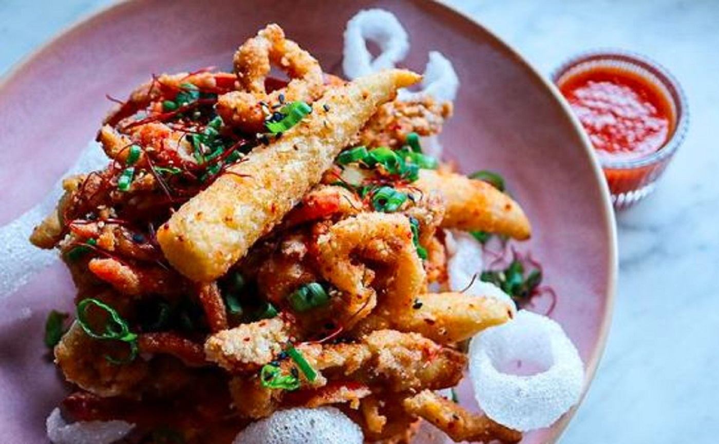 A pink plat piled with fried calamari.