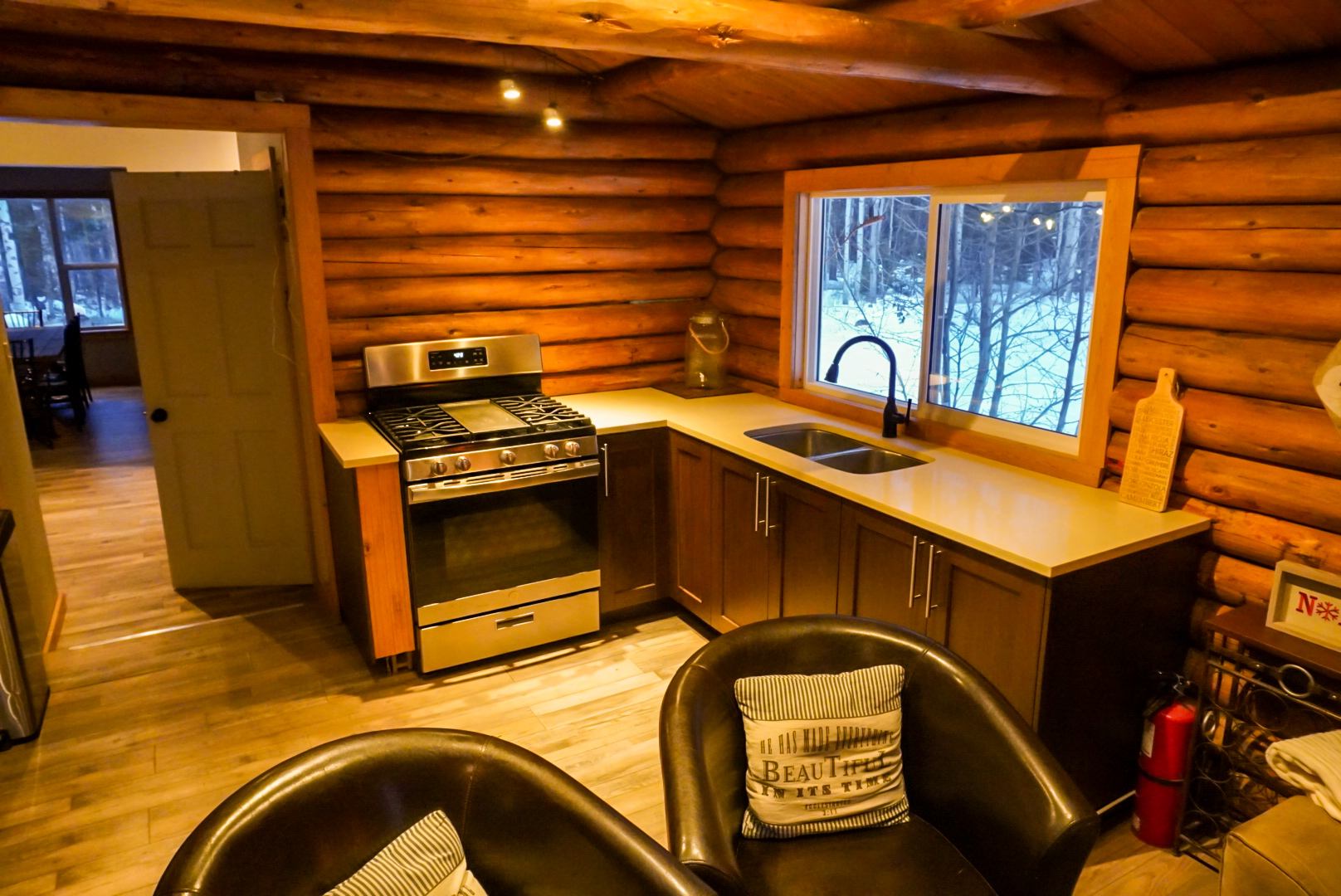 Rustic log cabin kitchen with stove, sink, and cozy seating at Trembling Aspen Retreat.