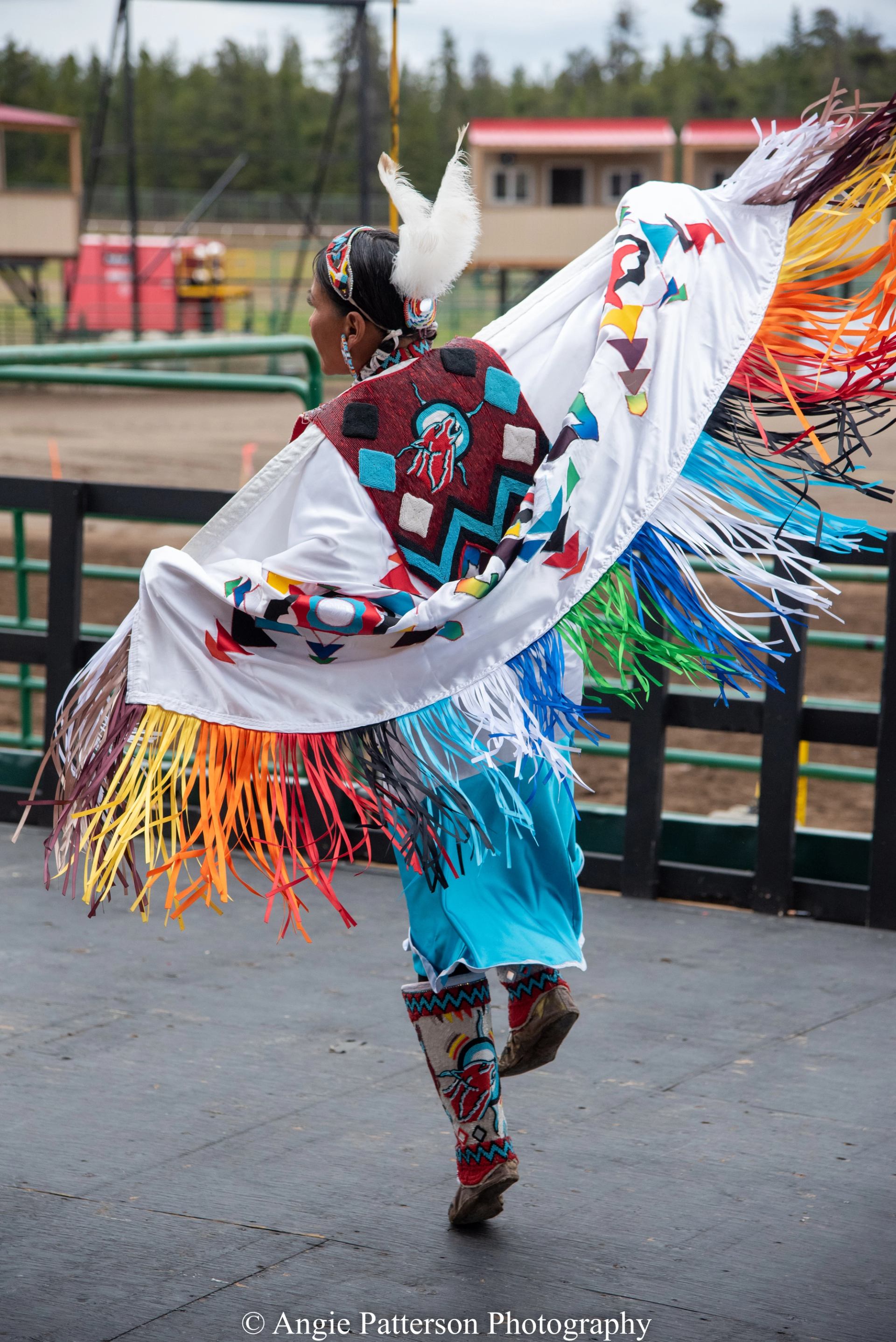 Performer dancing with a decorated shawl featuring colorful fringe.