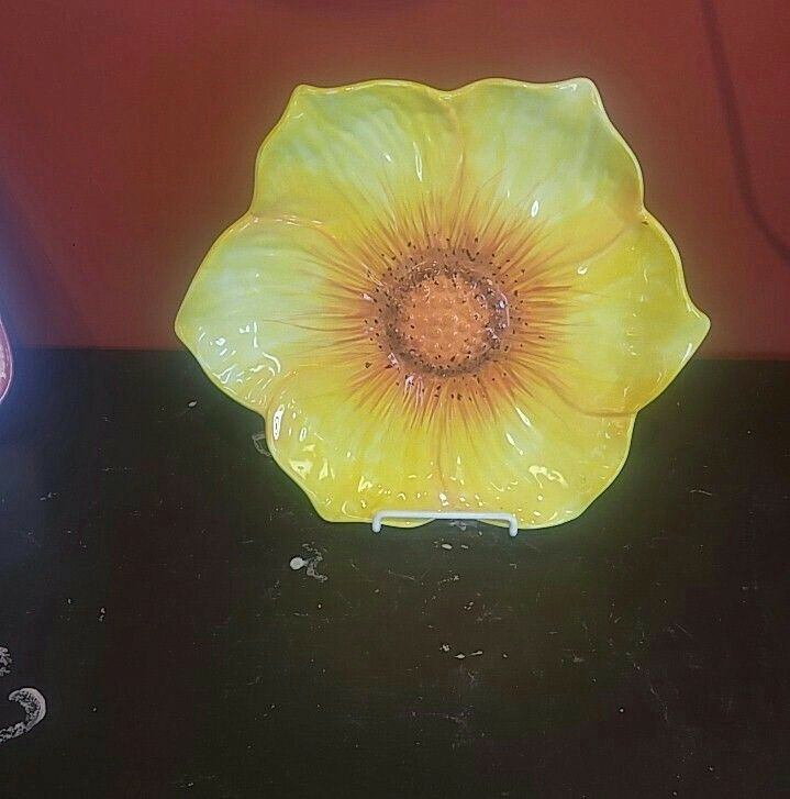 Green ceramic dish with flower design on black tabletop, with small paint splatters.