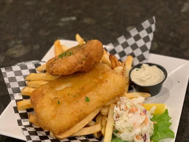 Plate of fish and chips with tartar sauce, coleslaw and lemon wedge.
