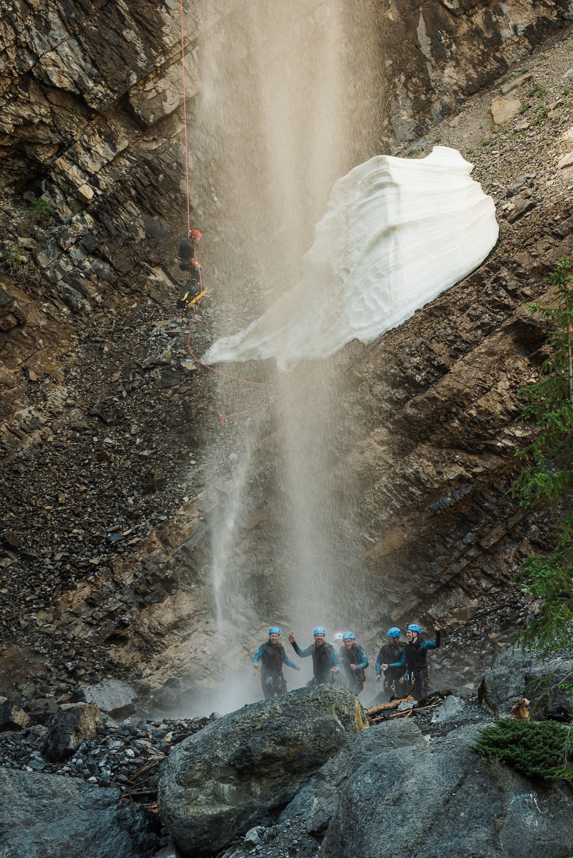 Group of friends celebrate while guide rappels.
