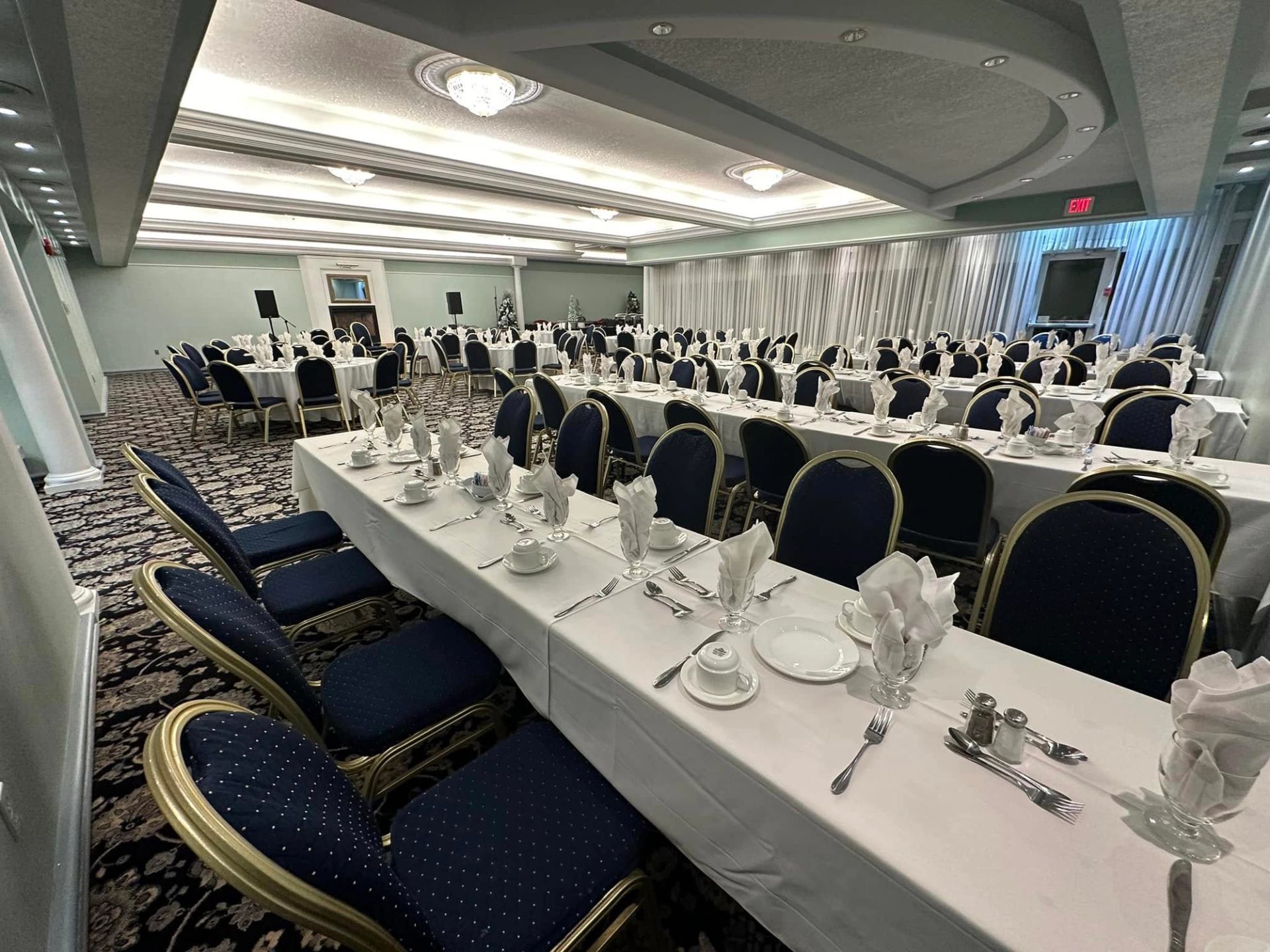 Banquet hall with long tables set with white linens, glassware and folded napkins.
