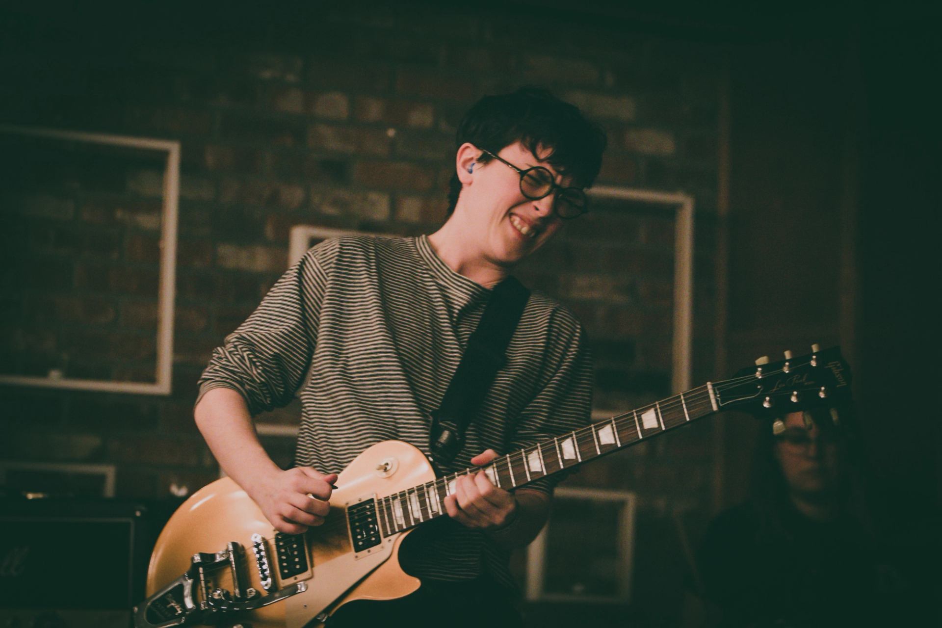 Musician playing an electric guitar on stage at Winterruption YEG with warm lighting.