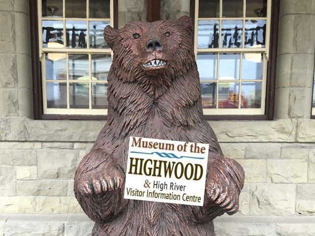 A wooden bear carving holding a welcome sign.