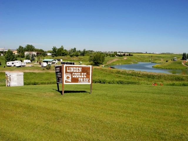 Linden Coulee Park sign with lake, RVs, and trees in the background.