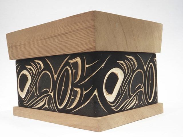 Wooden box with intricate native carvings and designs.