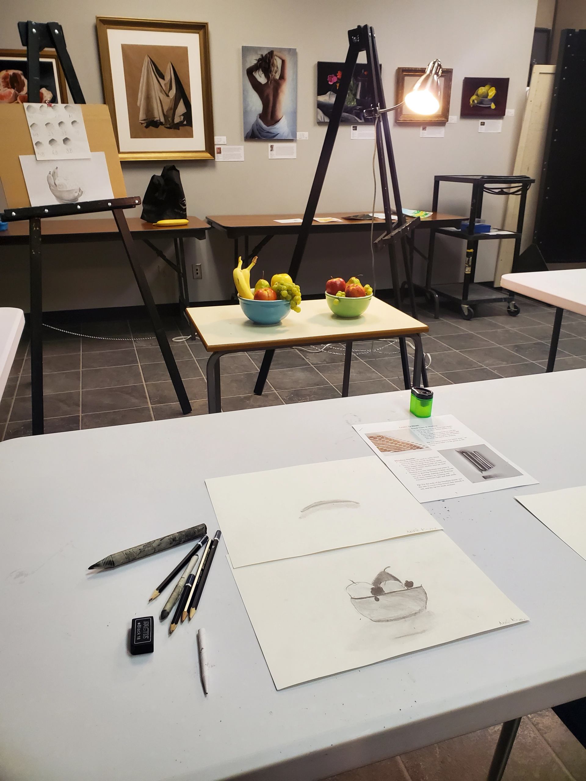 Art class setup with sketches, supplies, and still life arrangements.