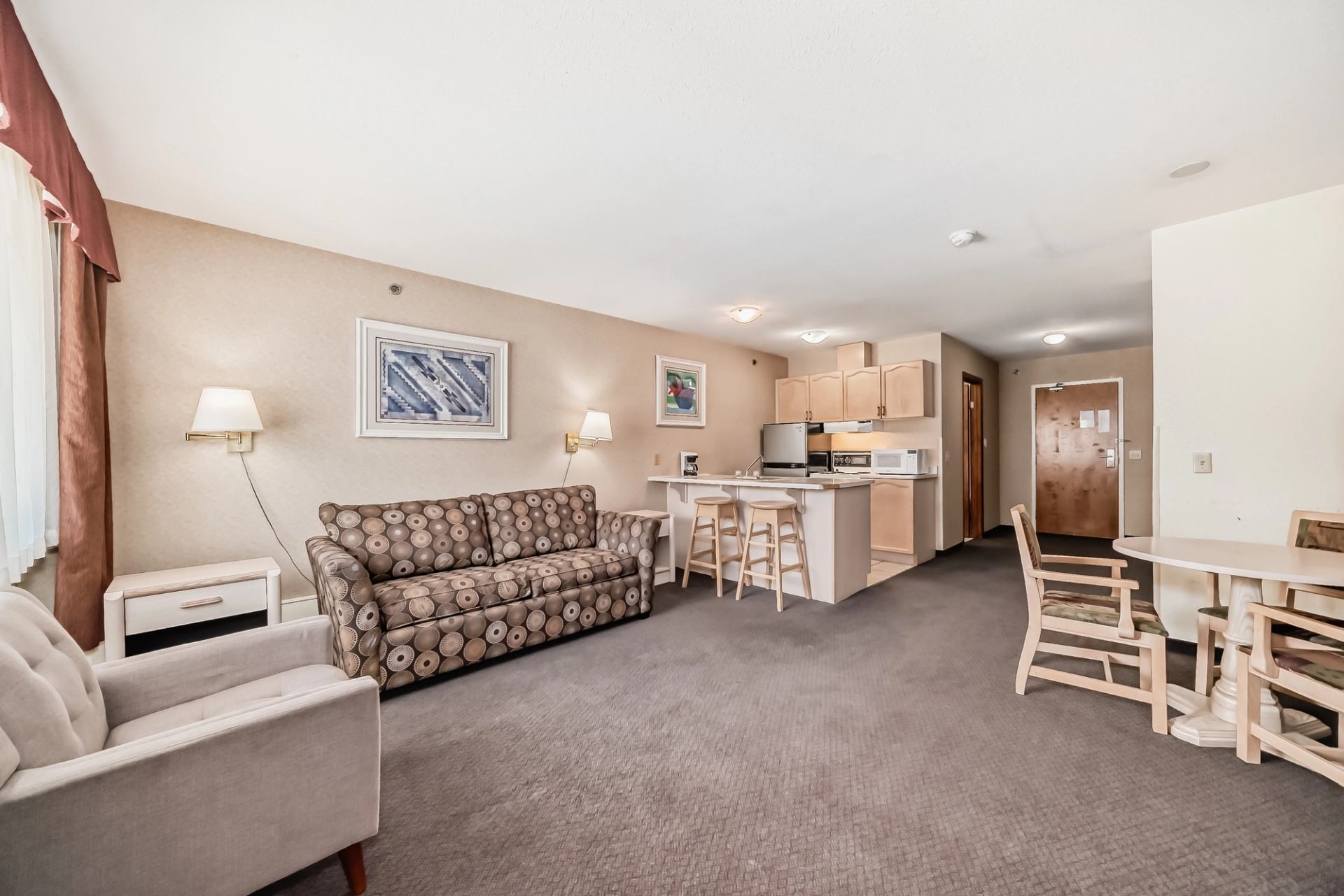 Hotel suite featuring a sofa, dining table, and full kitchen with stove and fridge