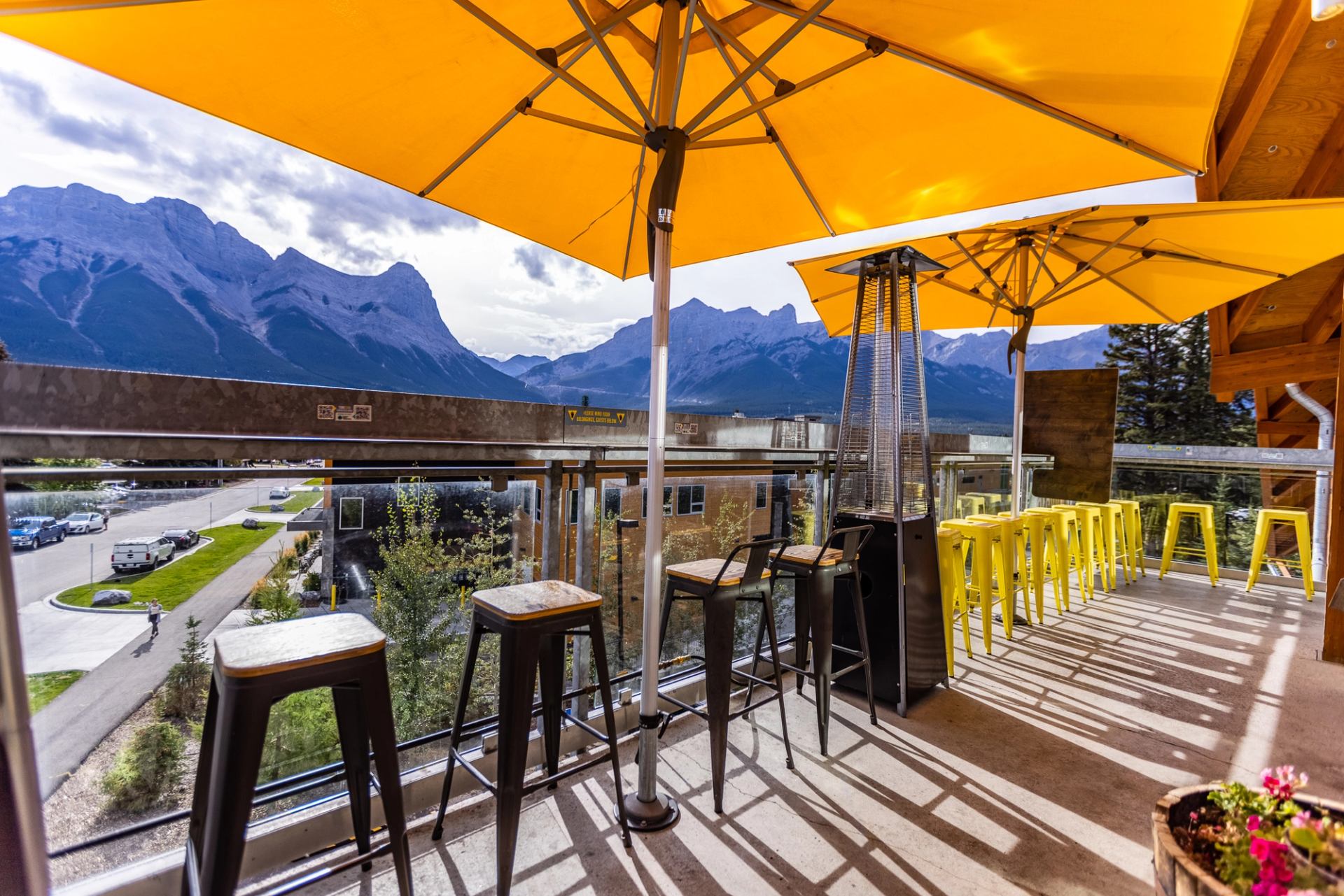 Outdoor patio with yellow umbrellas overlooking mountains at The Grizzly Paw Brewing Company.